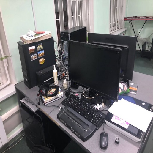 Чёрный рабочий стол, на котором стоит стационарный компьютер и оргтехника