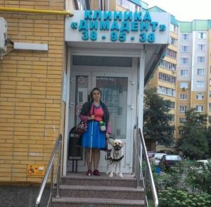 Анна Наумова с собакой-проводником на ступенях стоматологической клиники