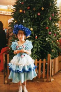 София Дидина в детстве стоит у новогодней ёлки в костюме снежинки