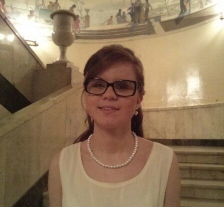 Аделина Ахунова - девушка в очках и светлом платье, стоит на лестнице театра