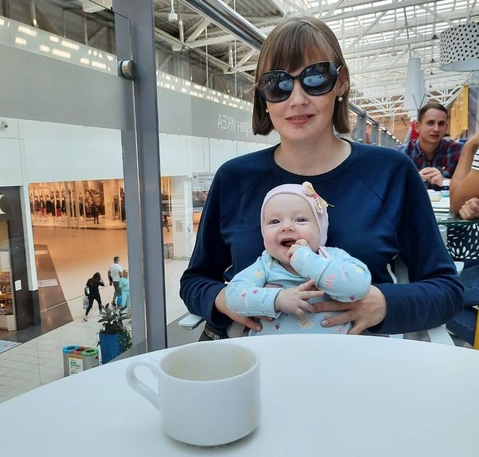 Ольга сидит с младенцем на руках за столиком в кафе