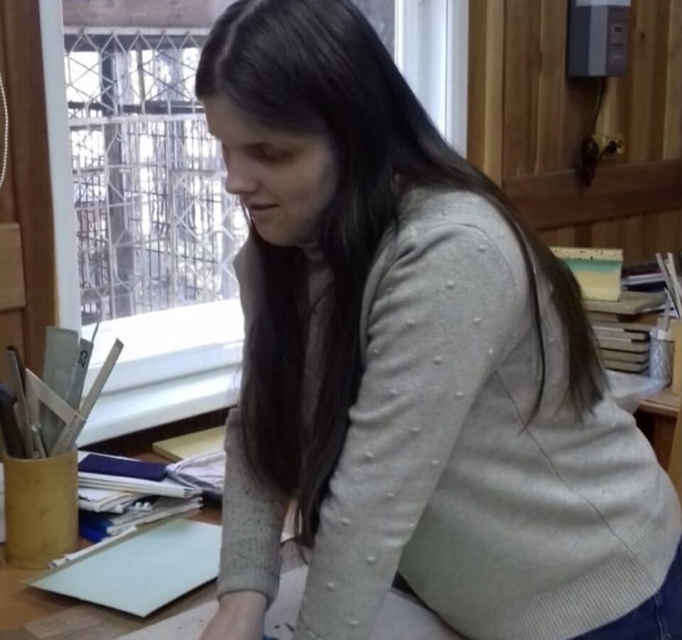 Анастасия Кузовкова в сером свитере стоит у стола в Бийском ЦРС