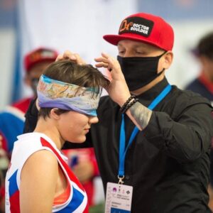 Оксана Осадчаяв спортивной форме, рядом с ней тренер, поправляет ей на голове напульсник