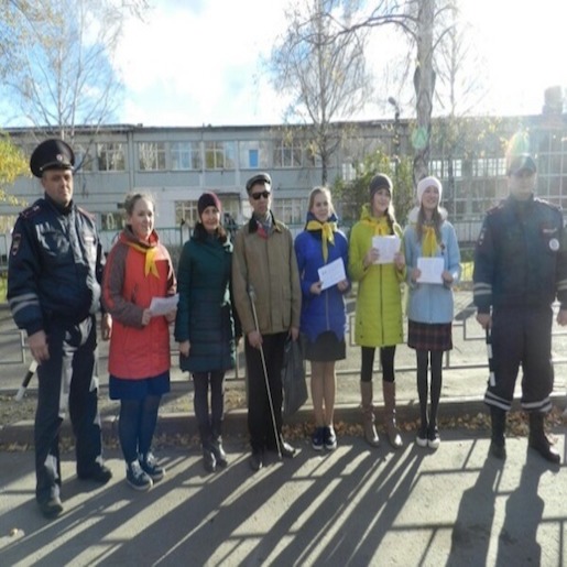 Евгений Петров с группой девушек стоит на фоне невысокого здания между двух мужчин в полицейской форме