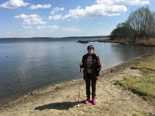 Маргарита Мельникова стоит с тростью на берегу реки