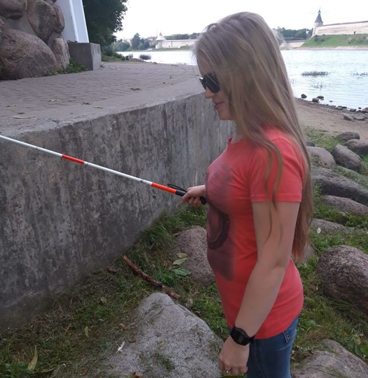 Ольга Сереброва стоит в профиль, смотрит тростью край гранитного блока