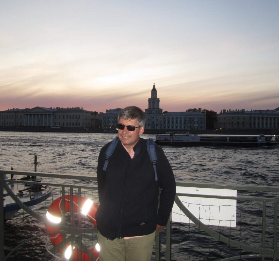 Сергей Парахин стоит у ограды набережной большой реки
