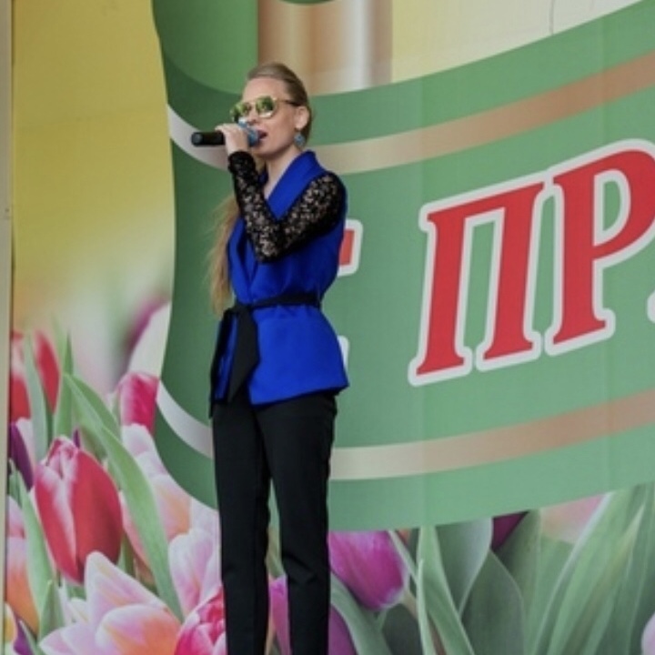 Кристина Томина стоит на сцене с микрофоном в руках