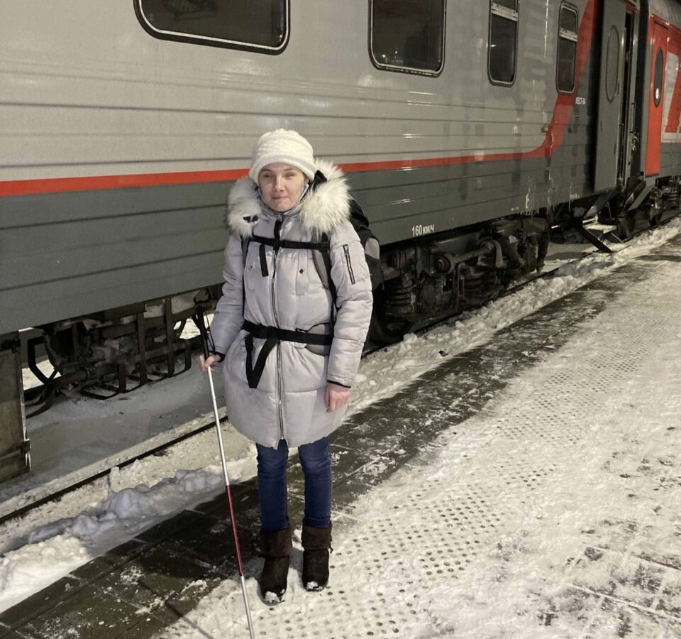 Екатерина Чернышова с тростью и большим походным рюкзаком на платформе у дверей поезда