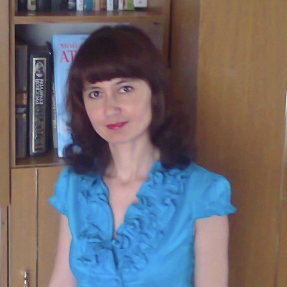 Нурия Мусаева в голубой блузке на фоне книжного шкафа